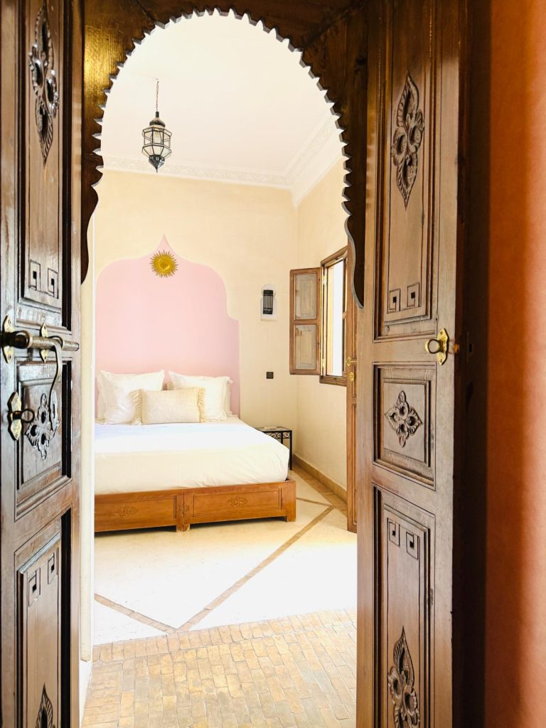 Suite Soleil du Riad Babmoon : tête de lit rose poudré et soleil doré en métal